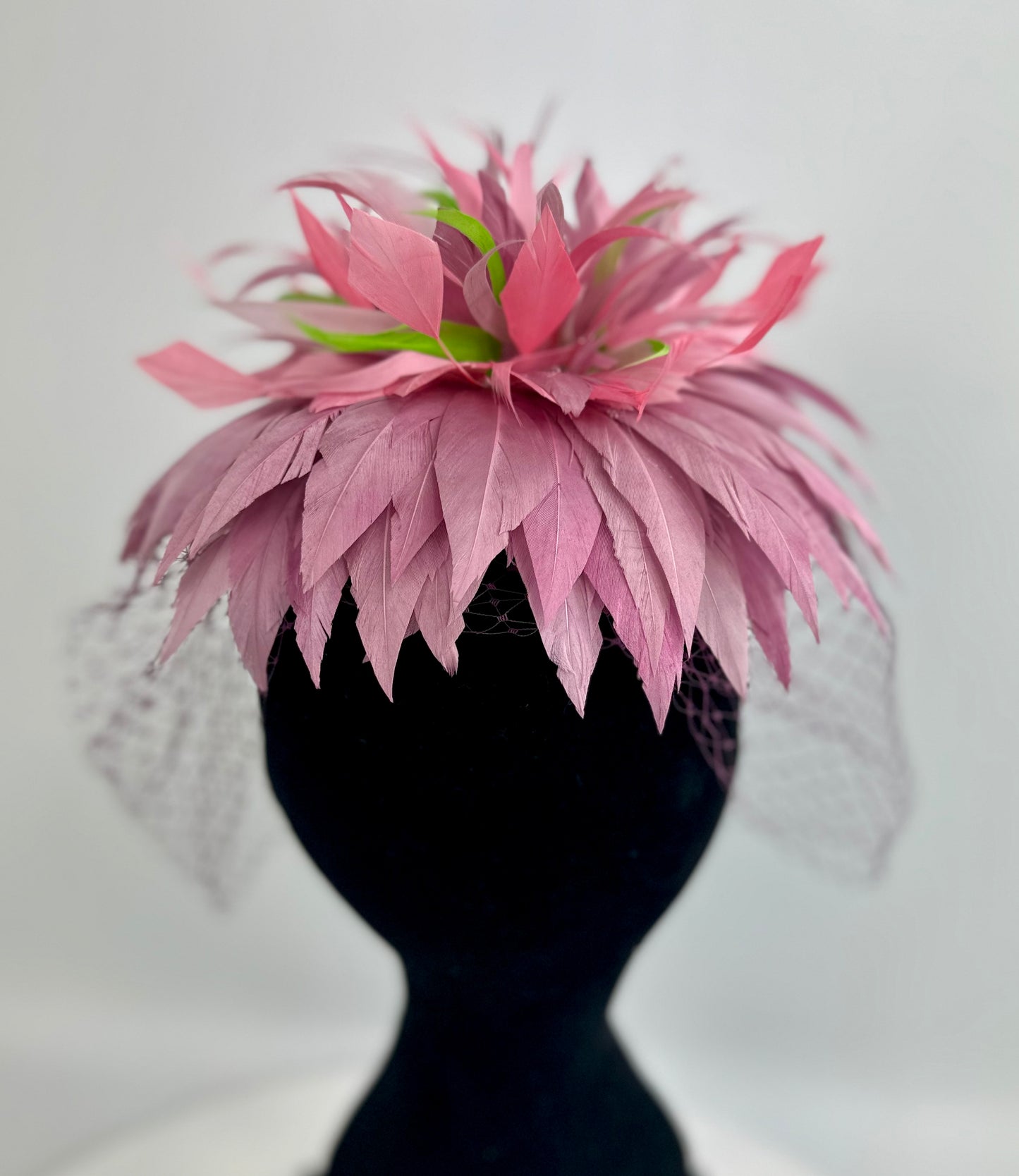 hat headpiece with purple and green feathers, purple veil netting on a white background