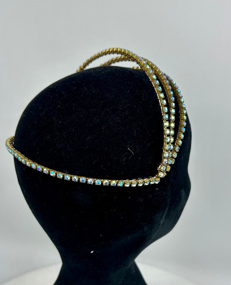 Three gold headbands with gemstones on a black mannequin head against a gray background