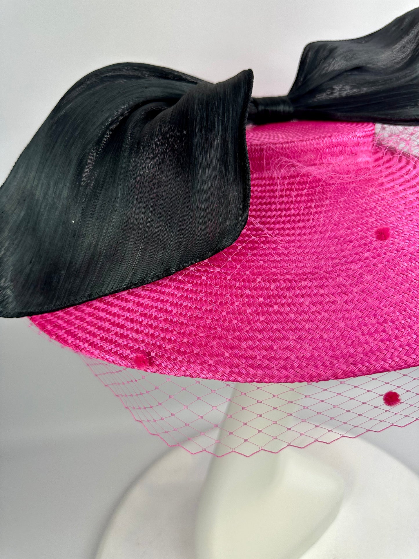 pink hat with veil and black bow on a white background
