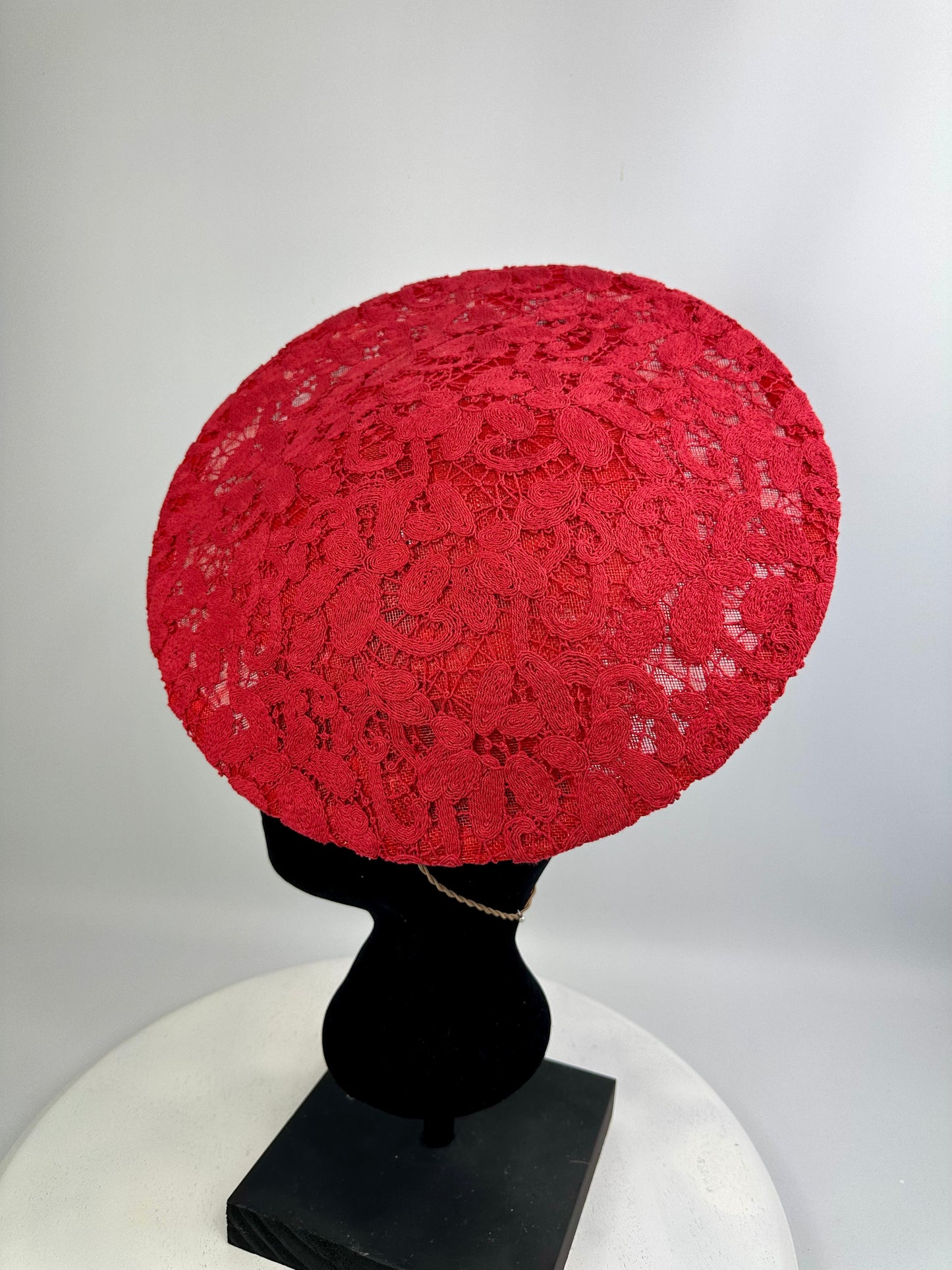 Red lace headpiece on a black mannequin head against a white background