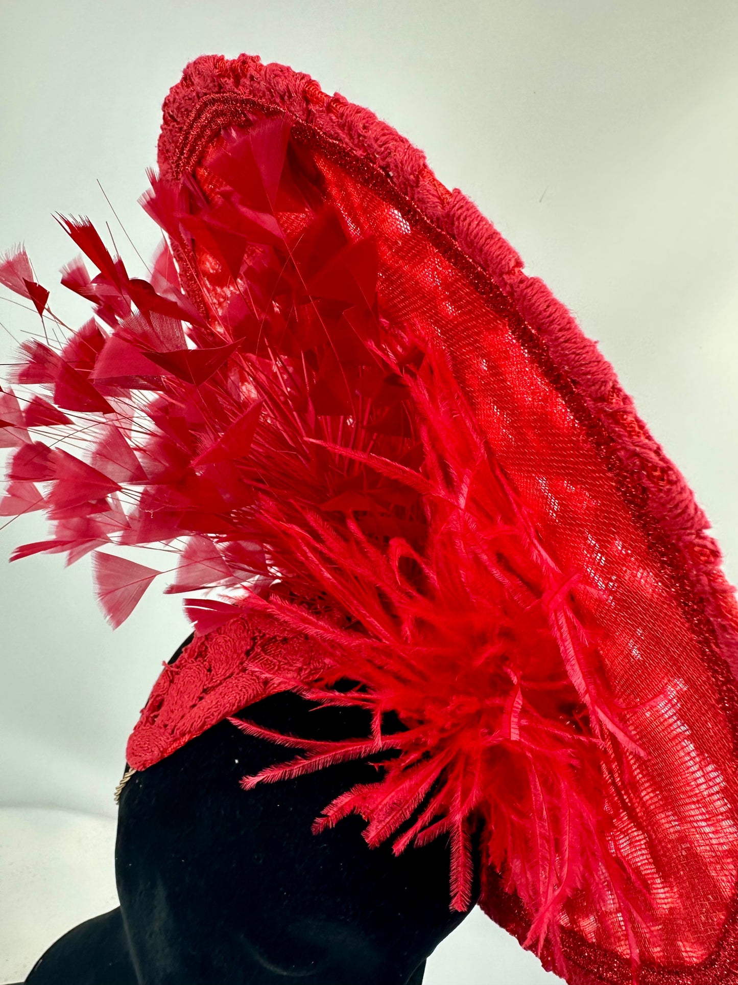 Red feathered hat on a mannequin head against a white background