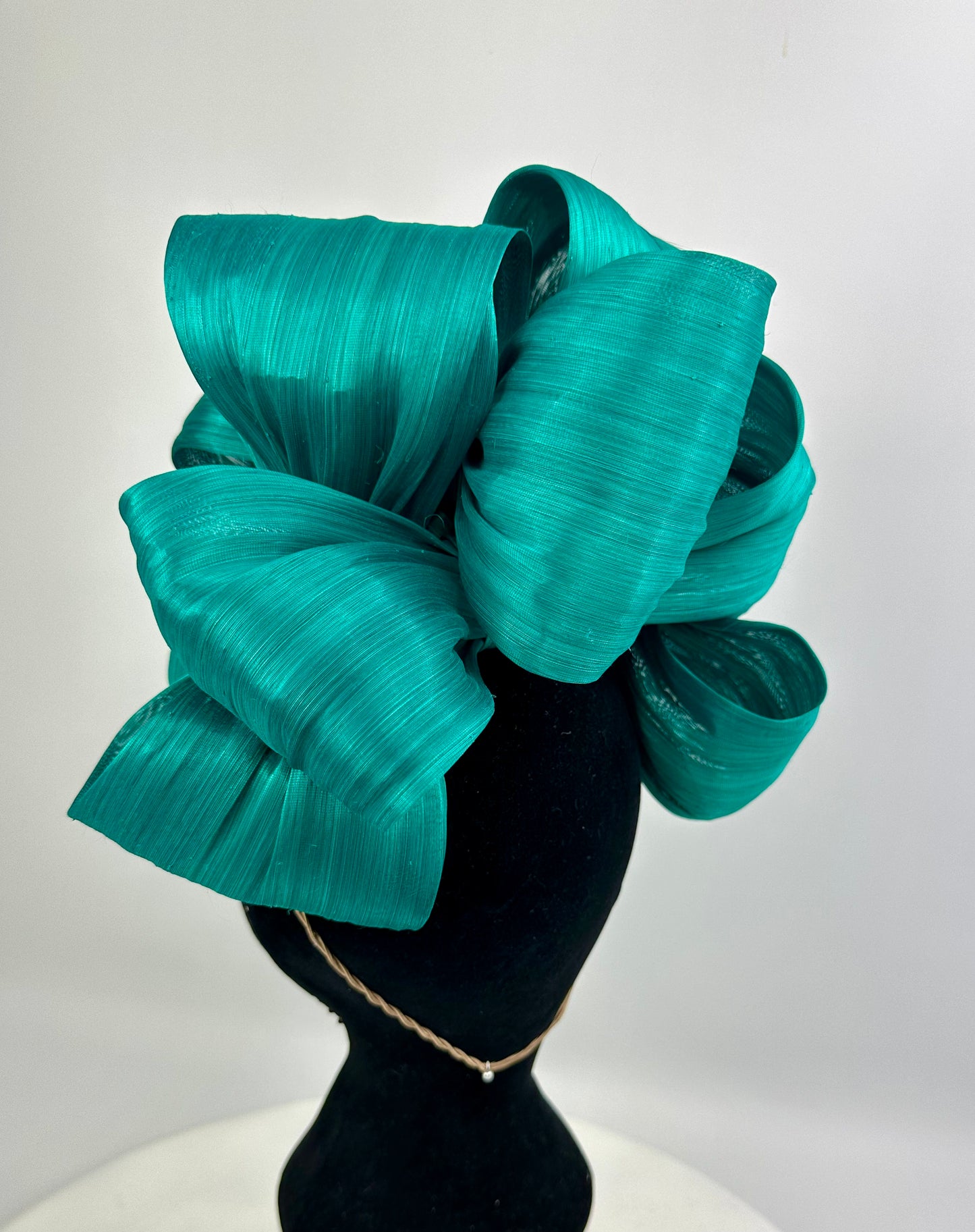 Teal bow headpiece on a mannequin head against a white background