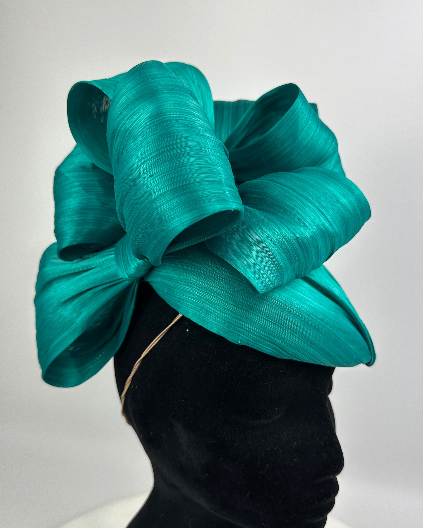 Teal bow headpiece on a mannequin against a white background