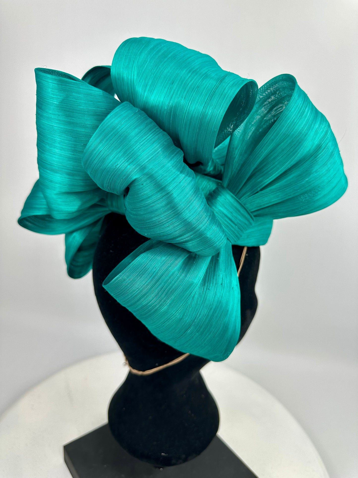 Turquoise bow headpiece on a mannequin head against a white background