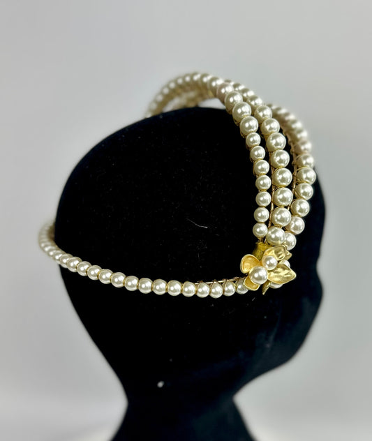 3 rows pearl headband with gold accents on a black stand against a gray background
