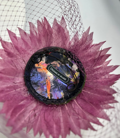 Underneath of hat headpiece with elastic, purple feathers, purple veil netting and 'Dezignz by Maree' label on a white background