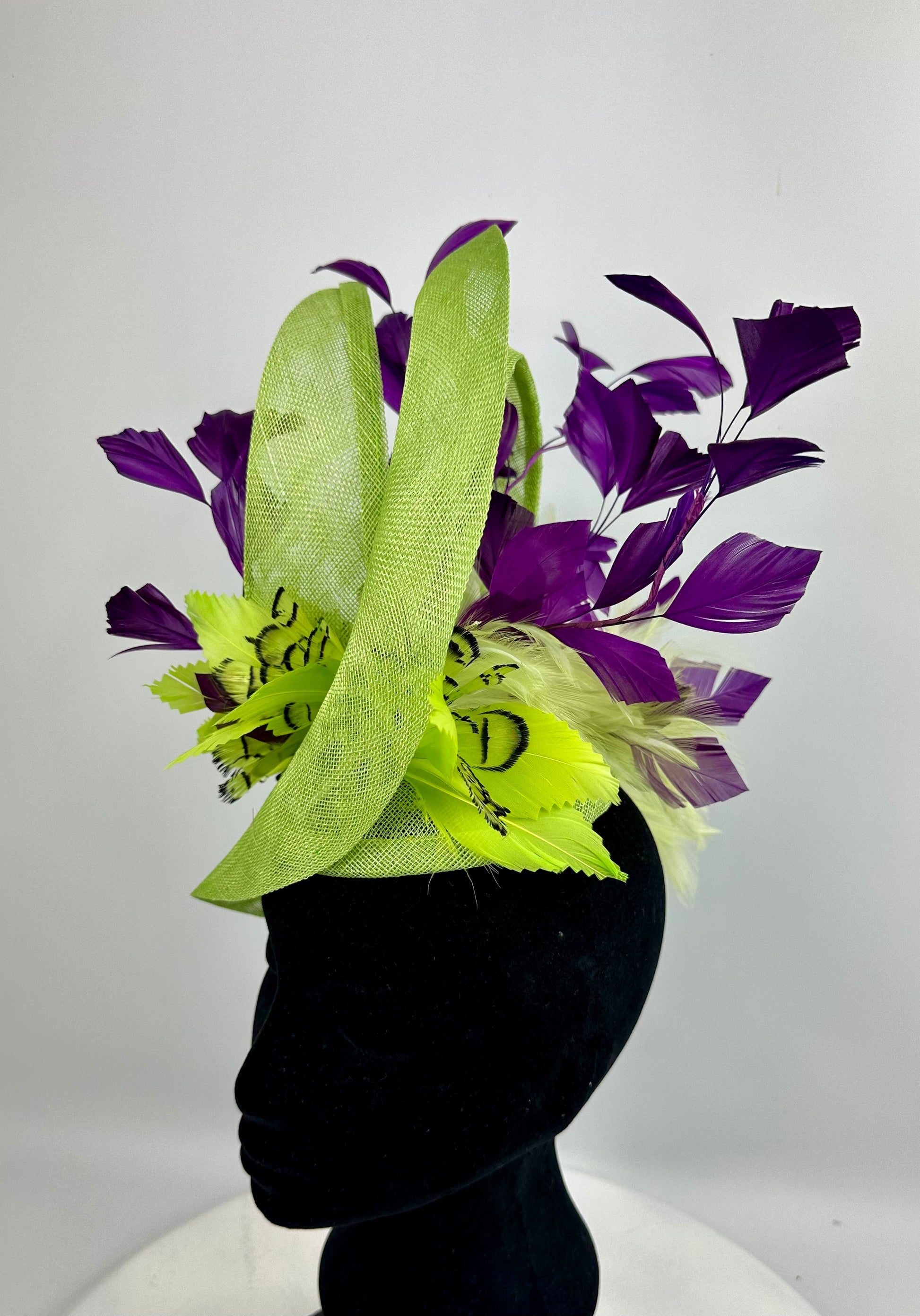 Fluro Green decorative headpiece hat with deep purple leaves and feathers on a white background