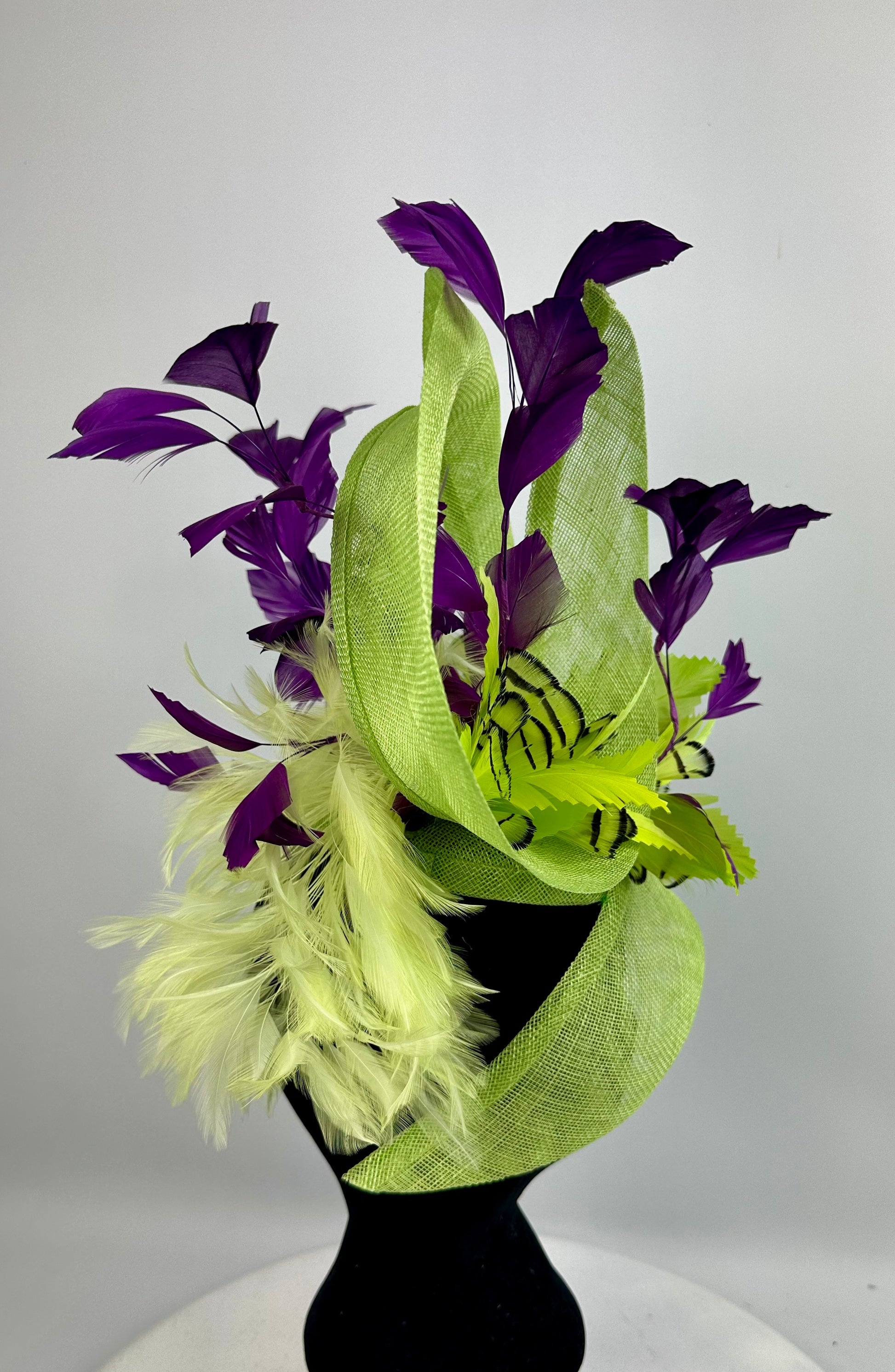 Fluro Green decorative headpiece hat with deep purple leaves and feathers on a white background