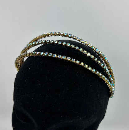 Three gold headbands with gemstones on a black mannequin head against a gray background
