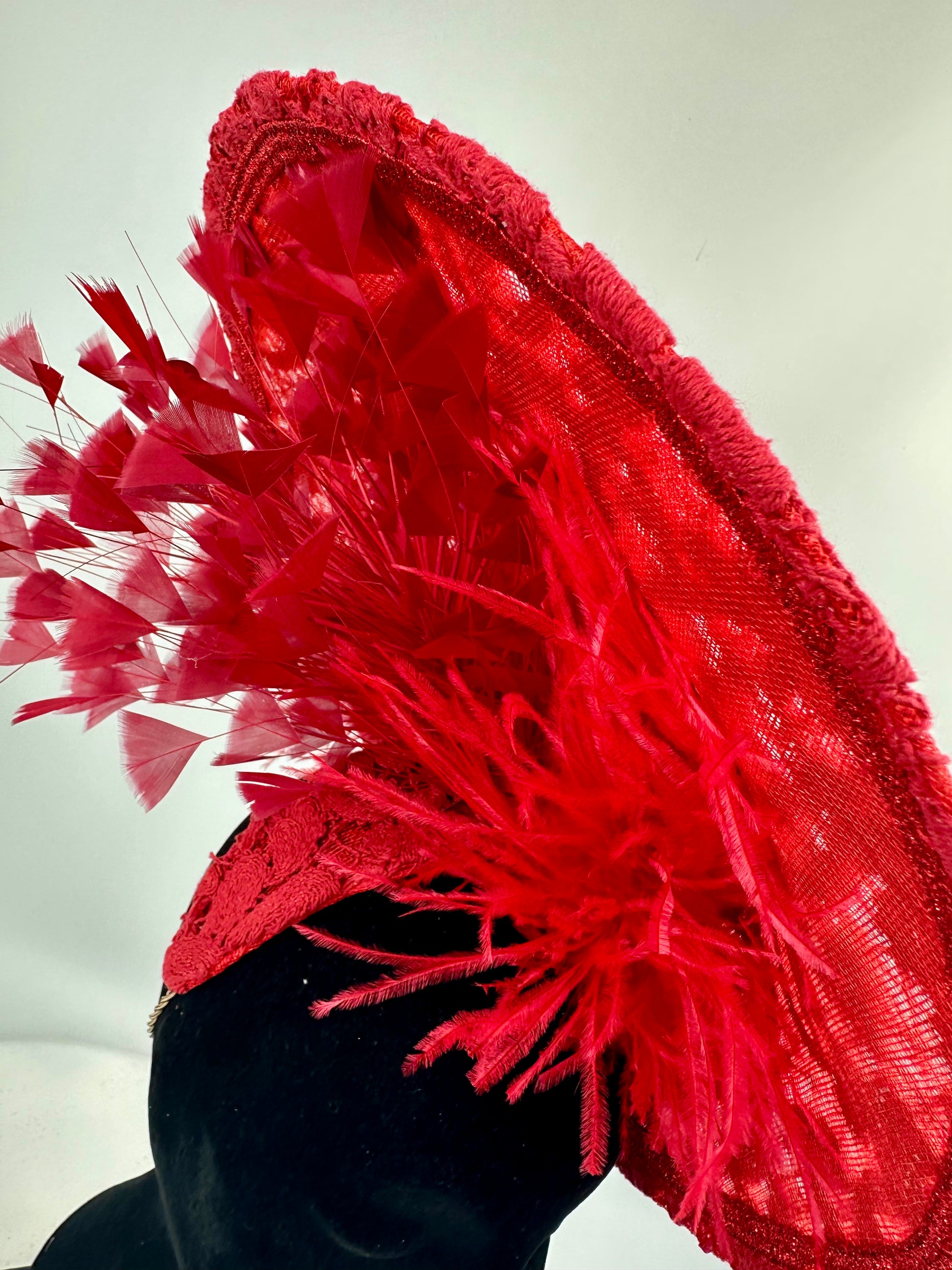 Red feathered hat on a mannequin head against a white background