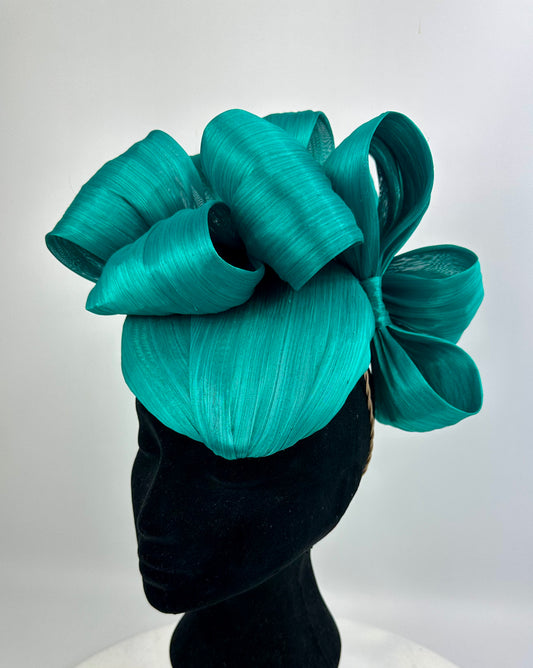 Teal bow headpiece on a mannequin head against a white background
