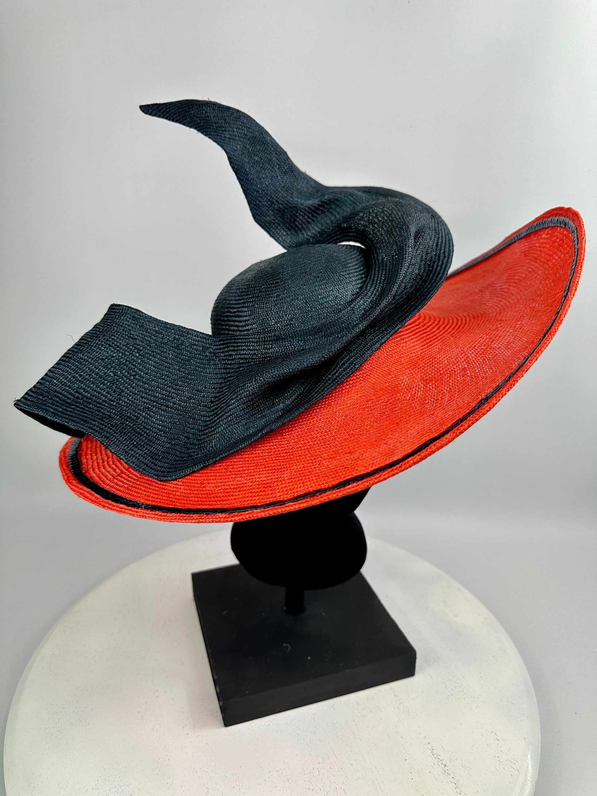 Black and orange wide-brimmed hat  with bow detail on a mannequin head against a white background