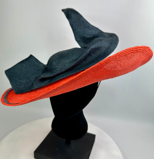 Black and orange wide-brimmed hat  with bow detail on a mannequin head against a white background