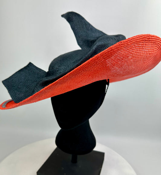 Black and orange wide-brimmed hat  with bow detail on a mannequin head against a white background