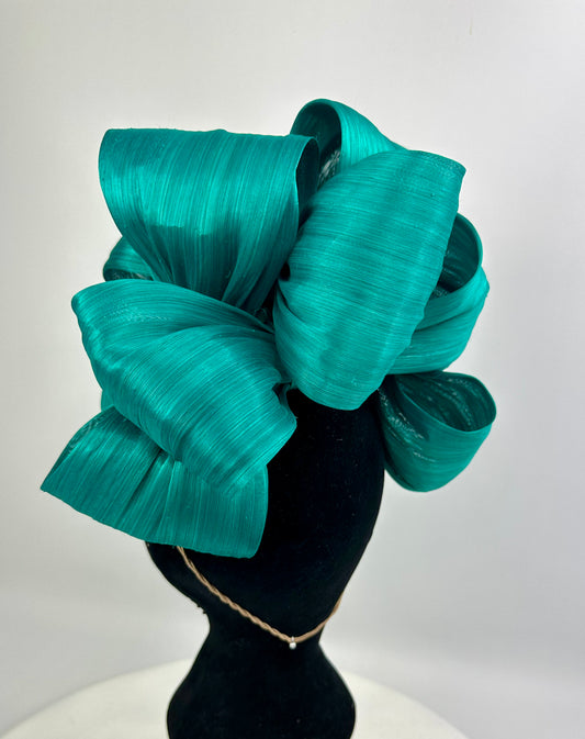 Teal bow headpiece on a mannequin head against a white background