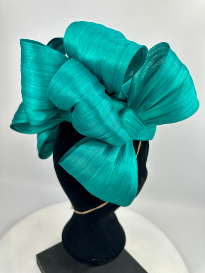 Turquoise bow headpiece on a mannequin head against a white background